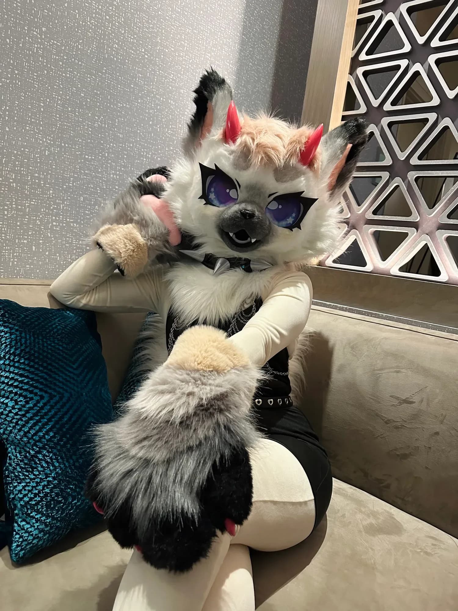 A wolf-style fursuiter posed on a lobby couch at Anthro Northwest 2026.
